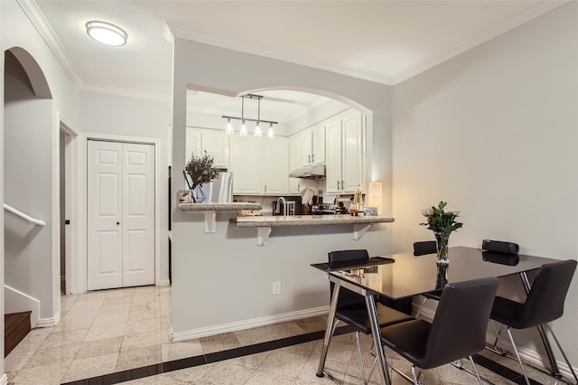 interior space featuring pendant lighting, white cabinetry, stainless steel refrigerator, crown molding, and a kitchen bar