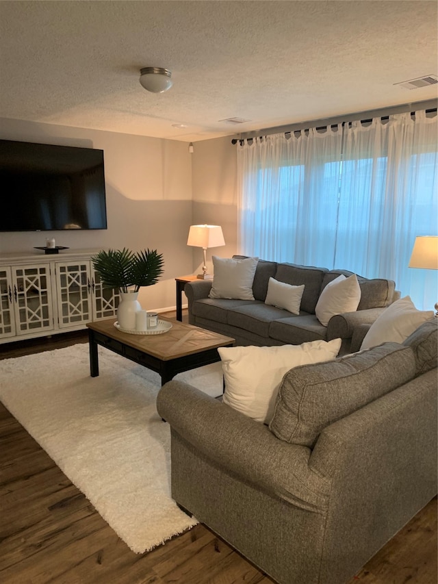 living room with a textured ceiling and dark hardwood / wood-style floors