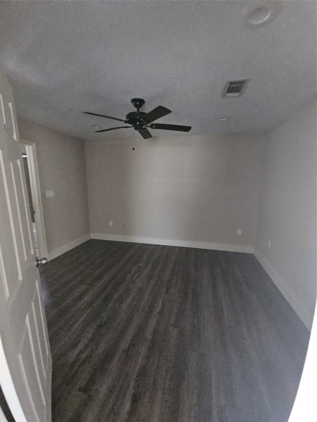 unfurnished room featuring ceiling fan, dark wood-type flooring, and a textured ceiling