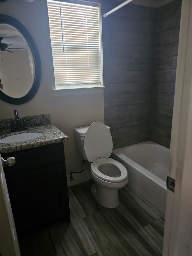 full bathroom with ceiling fan, tiled shower / bath, vanity, and toilet