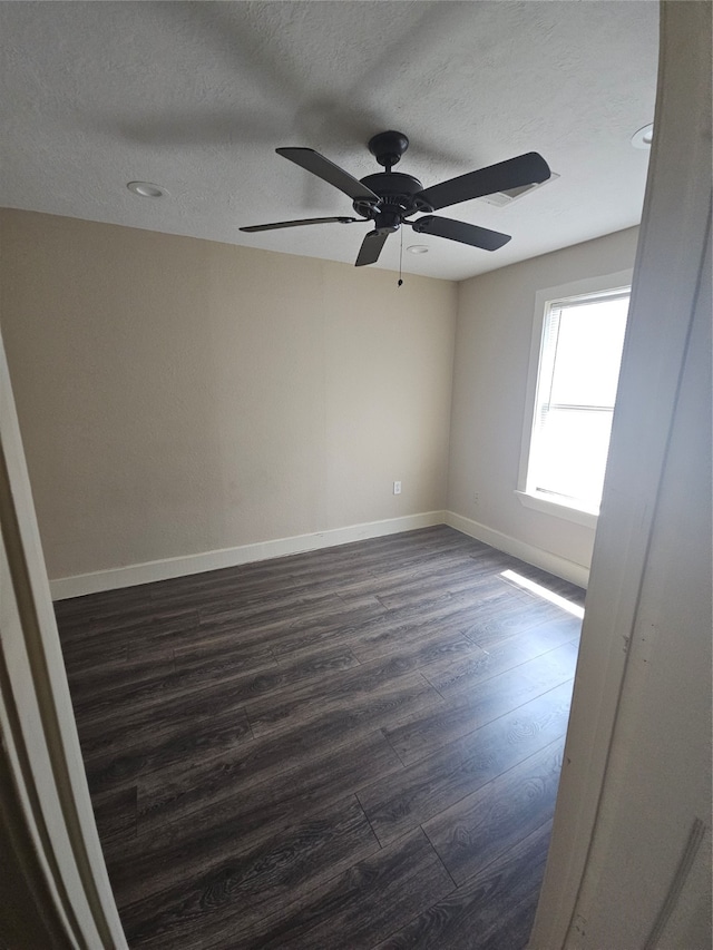 unfurnished room featuring ceiling fan, dark hardwood / wood-style floors, and a textured ceiling