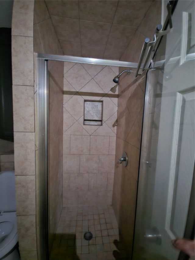 bathroom featuring toilet and a shower with shower door