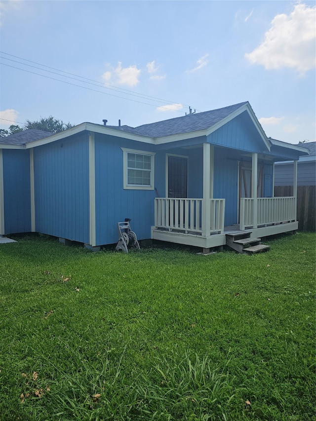 back of property with a yard and covered porch