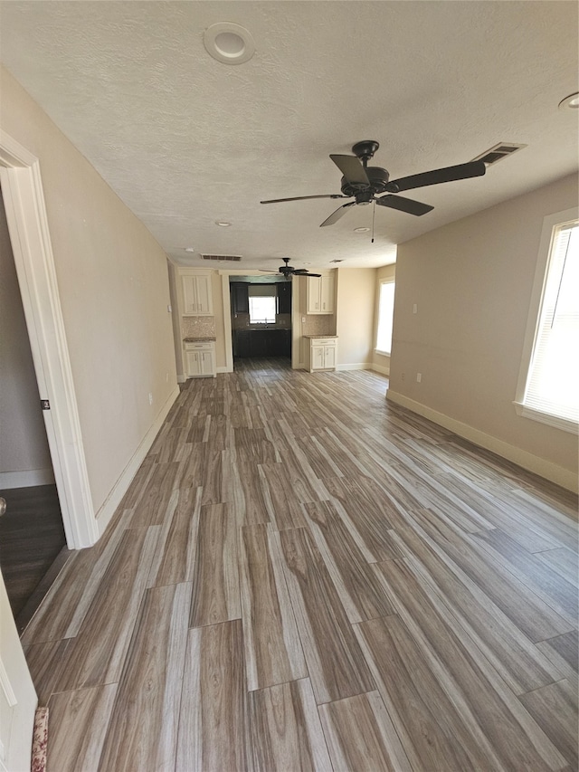 unfurnished living room featuring a textured ceiling, wood-type flooring, and ceiling fan