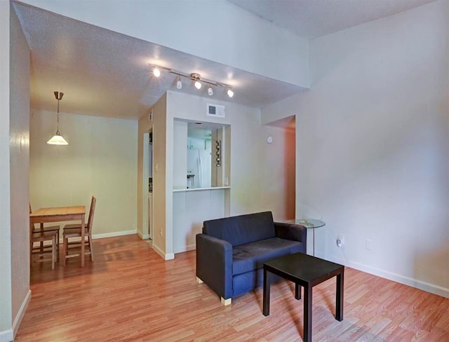 living area featuring a textured ceiling, light wood-type flooring, and rail lighting