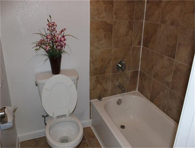 bathroom with tiled shower / bath combo, tile patterned flooring, and toilet