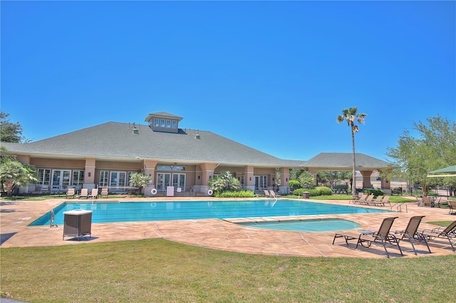 view of pool with a patio and a lawn