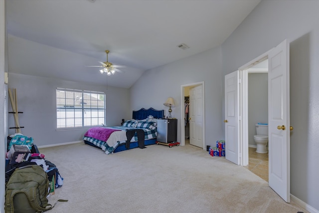 bedroom with ceiling fan, connected bathroom, vaulted ceiling, a walk in closet, and light colored carpet