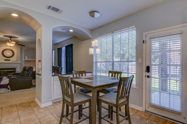 tiled dining area with ceiling fan and plenty of natural light