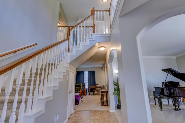 staircase with ornamental molding, a high ceiling, and carpet flooring