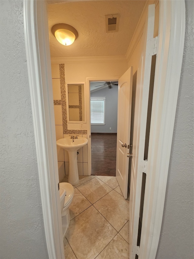 bathroom featuring tile patterned flooring, sink, a textured ceiling, crown molding, and toilet