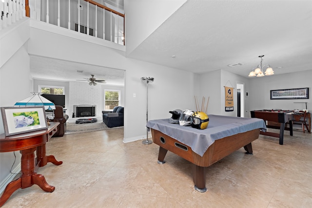 recreation room with pool table, ceiling fan with notable chandelier, and a brick fireplace