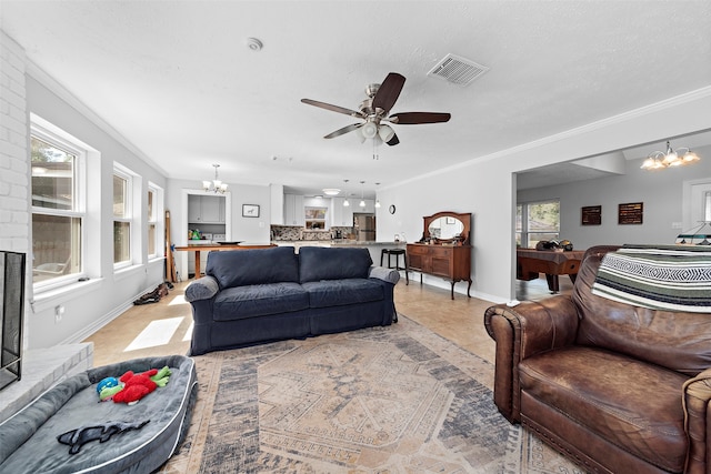 living room featuring ceiling fan with notable chandelier, a fireplace, ornamental molding, and plenty of natural light