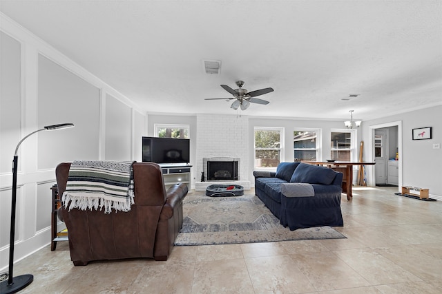 living room with ceiling fan with notable chandelier, a fireplace, and ornamental molding