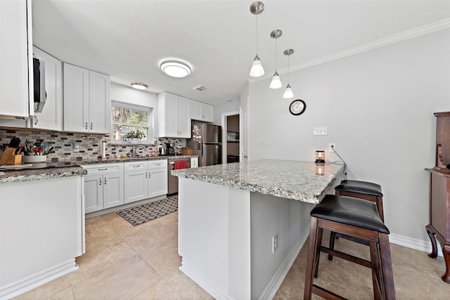 kitchen featuring pendant lighting, light stone counters, white cabinets, decorative backsplash, and stainless steel appliances