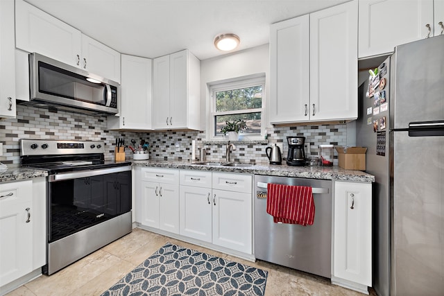 kitchen featuring light stone counters, white cabinets, backsplash, stainless steel appliances, and sink