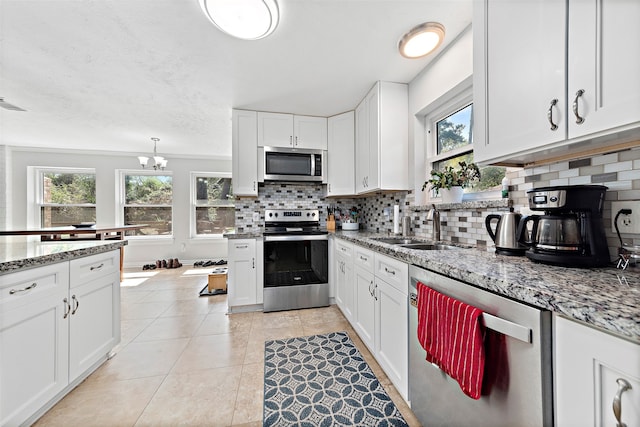 kitchen with decorative backsplash, white cabinets, appliances with stainless steel finishes, and plenty of natural light