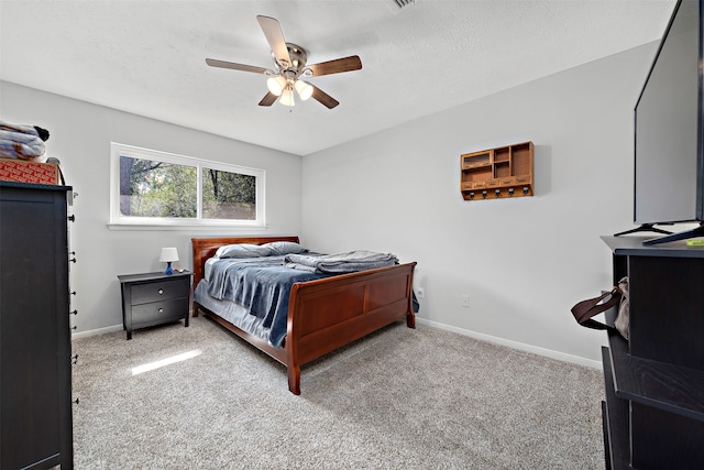 carpeted bedroom featuring ceiling fan and a textured ceiling