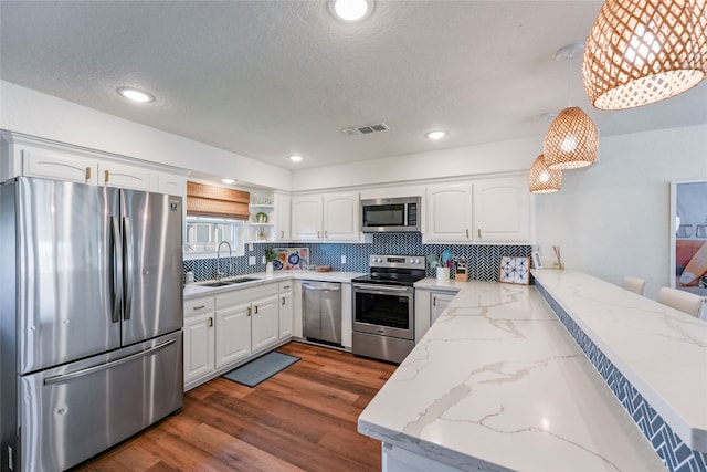 kitchen with stainless steel appliances, white cabinets, decorative light fixtures, and sink