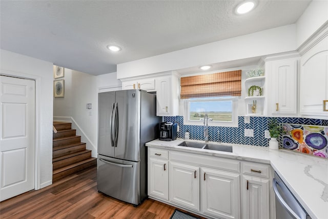 kitchen with light stone counters, dark hardwood / wood-style floors, sink, white cabinetry, and appliances with stainless steel finishes