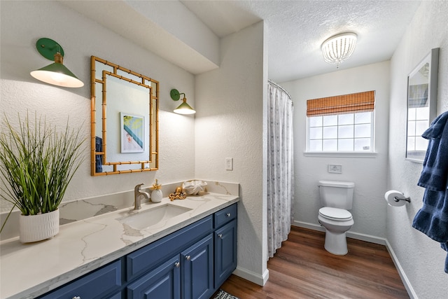 bathroom with vanity, toilet, a textured ceiling, and hardwood / wood-style flooring