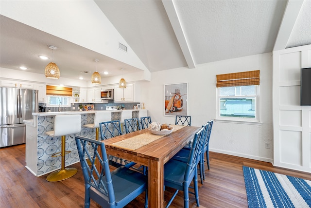 dining room with lofted ceiling with beams, a textured ceiling, dark wood-type flooring, and sink