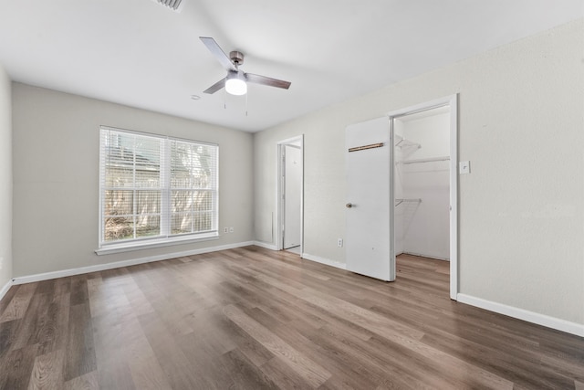 unfurnished bedroom with ceiling fan, a closet, hardwood / wood-style floors, and a spacious closet