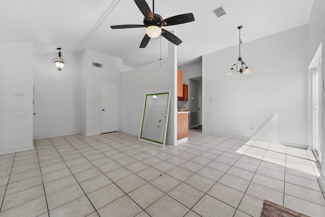 tiled spare room featuring ceiling fan with notable chandelier and a high ceiling