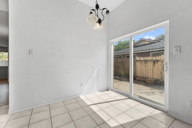 tiled empty room with vaulted ceiling and an inviting chandelier