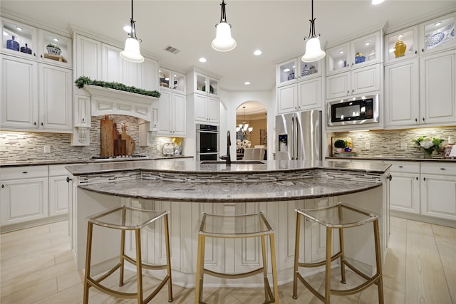 kitchen featuring appliances with stainless steel finishes, white cabinets, a center island, and decorative light fixtures