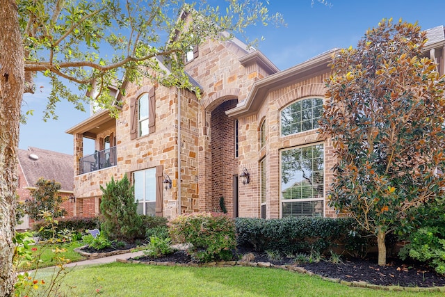 view of front of house featuring a balcony and a front lawn