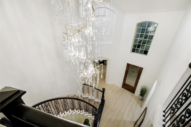 entryway with wood-type flooring, a notable chandelier, and crown molding