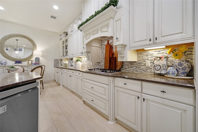 kitchen with light wood-type flooring, tasteful backsplash, white cabinetry, appliances with stainless steel finishes, and ornamental molding