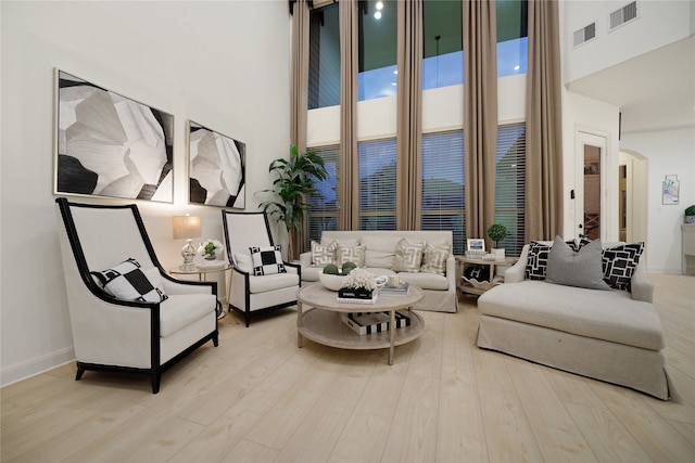 living room featuring a towering ceiling and light hardwood / wood-style flooring