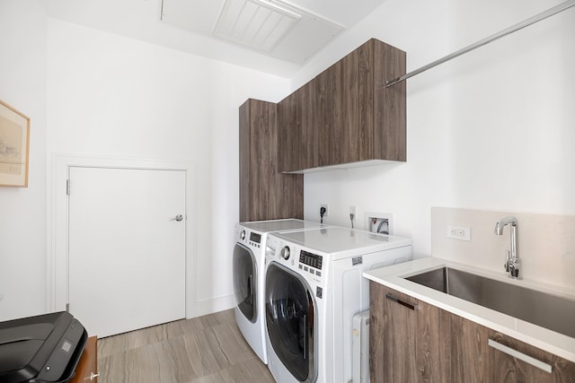 washroom with cabinets, sink, and washing machine and clothes dryer