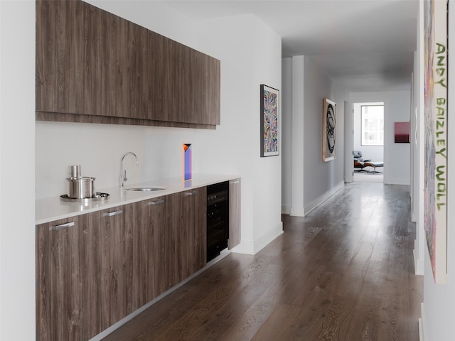 bar with dark brown cabinets, sink, dark wood-type flooring, and wine cooler