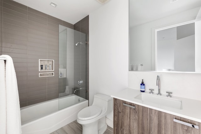 full bathroom with wood-type flooring, tiled shower / bath, vanity, and toilet