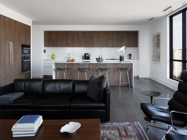 living room featuring a wealth of natural light and dark wood-type flooring