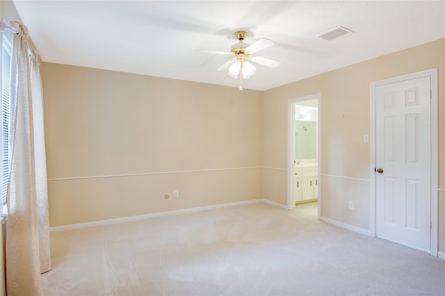 unfurnished bedroom with ensuite bath, ceiling fan, and light carpet