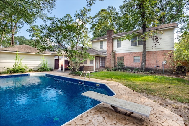 view of swimming pool featuring a yard, a diving board, and a patio area