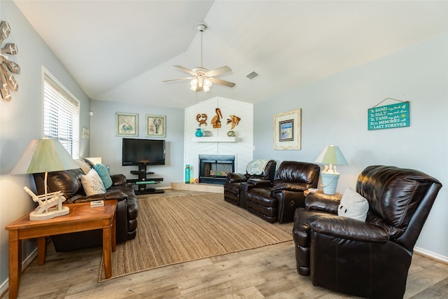 living room with a tile fireplace, lofted ceiling, ceiling fan, and light hardwood / wood-style flooring