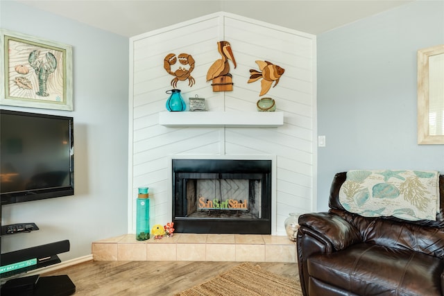 living room featuring a tiled fireplace and hardwood / wood-style floors