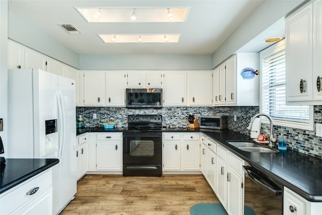 kitchen with sink, light hardwood / wood-style flooring, backsplash, white cabinetry, and black appliances