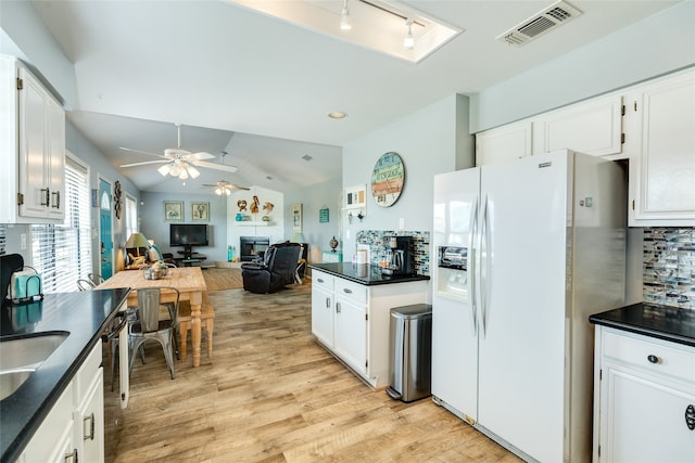 kitchen with ceiling fan, white cabinets, white refrigerator with ice dispenser, light wood-type flooring, and vaulted ceiling