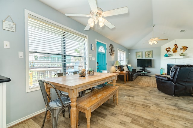 dining room featuring ceiling fan, lofted ceiling, light wood-type flooring, and a healthy amount of sunlight