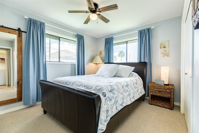 carpeted bedroom with a barn door, ceiling fan, and multiple windows