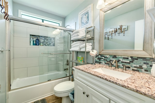 full bathroom with shower / bath combination with glass door, vanity, tasteful backsplash, wood-type flooring, and toilet