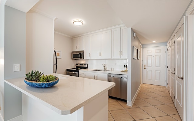 kitchen with kitchen peninsula, appliances with stainless steel finishes, sink, light tile patterned floors, and white cabinets