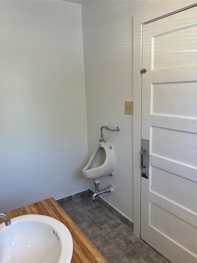 bathroom featuring baseboards, a bidet, a sink, and tile patterned floors