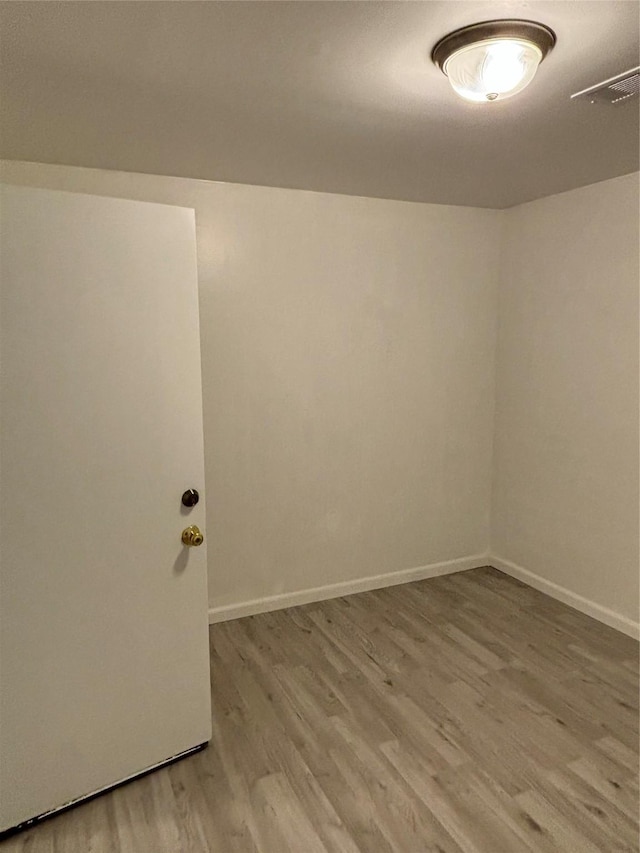 spare room with light wood finished floors, visible vents, and baseboards